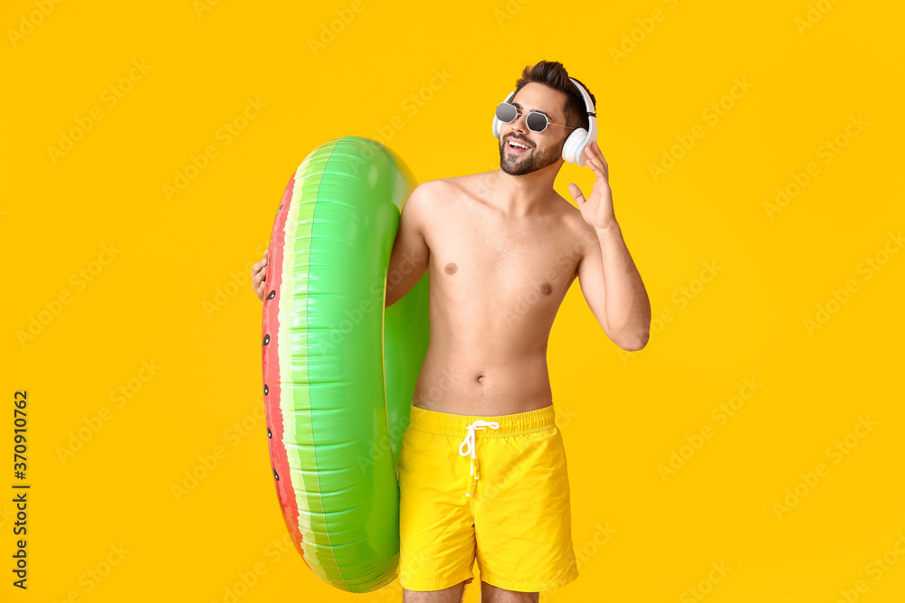 Young man with headphones and inflatable ring on color background Young man with headphones and inflatable ring on color background