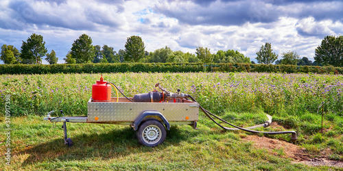 Water pump with motor on a car trailer in a field.