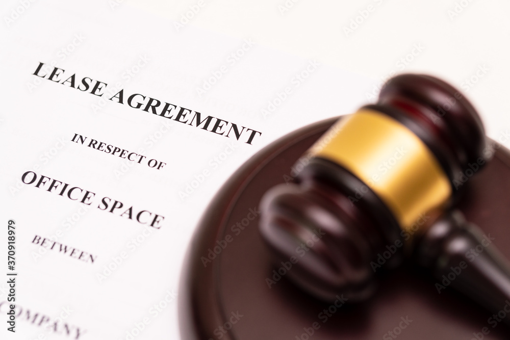 Concept of lease law or tenancy law: the cover of lease agreement was is placed near the blurred wooden gavel.