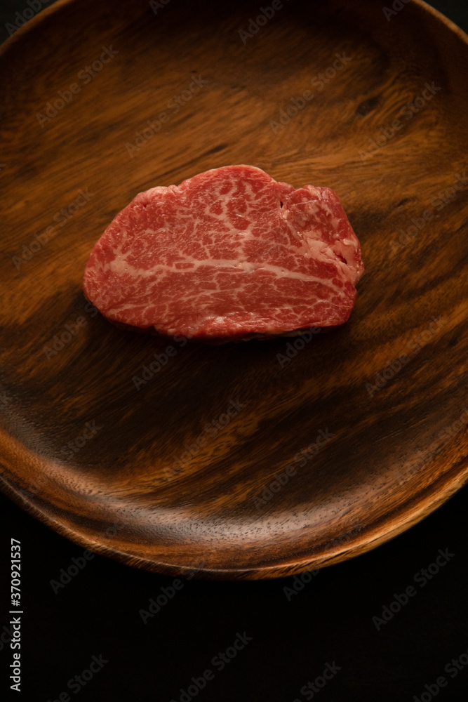 Raw Fillet Mignon Steak on the wooden round plate