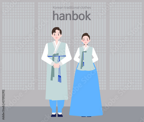 A male and female couple standing side by side in Korean traditional clothes, Hanbok, in front of a Korean traditional house