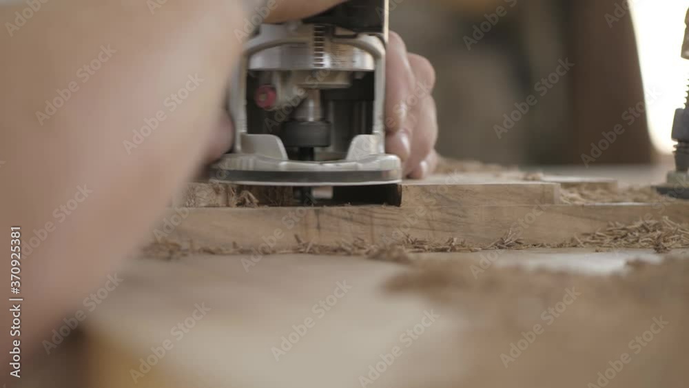 carpenter works with a manual electric milling cutter. woodworker processes a wooden board