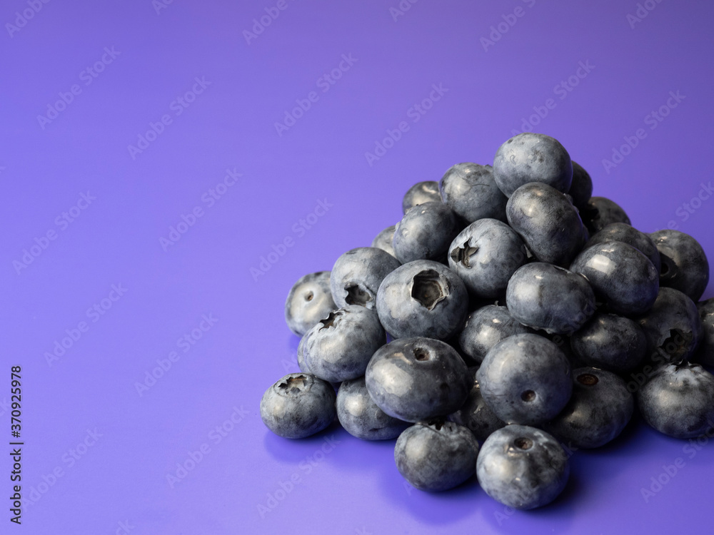 Pile of blueberries on purple background.