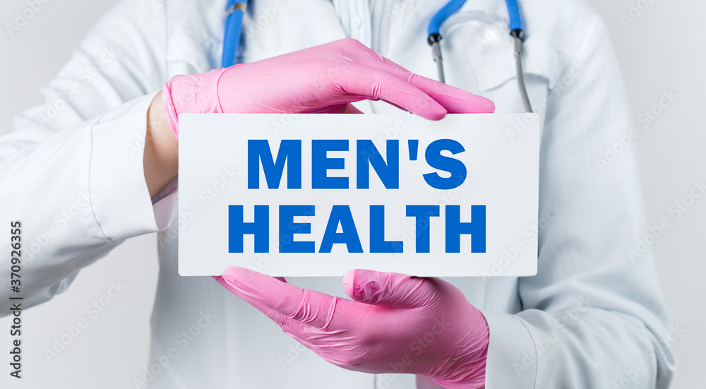 Cropped view of young female doctor in a white coat and pink sterile gloves holding a card with text MEN'S HEALTH. Medical concept. Cropped view of young female doctor in a white coat and pink sterile gloves holding a card with text MEN'S HEALTH. Medical concept.