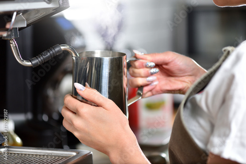 Young girl barista makes coffee on a large professional coffee machine, hands closeup. The concept of a small business and work for a student.