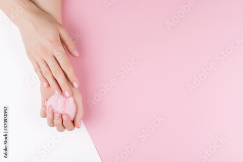 Beautiful women's hands with a stylish pink manicure on a pink and white background with a furry lump in hand