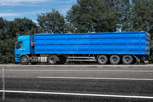 truck on the road, side view, empty space on a blue container - concept of cargo transportation, trucking industry