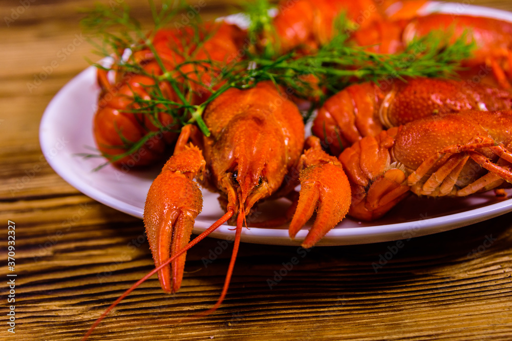 Plate with boiled crayfishes on wooden table Plate with boiled crayfishes on wooden table