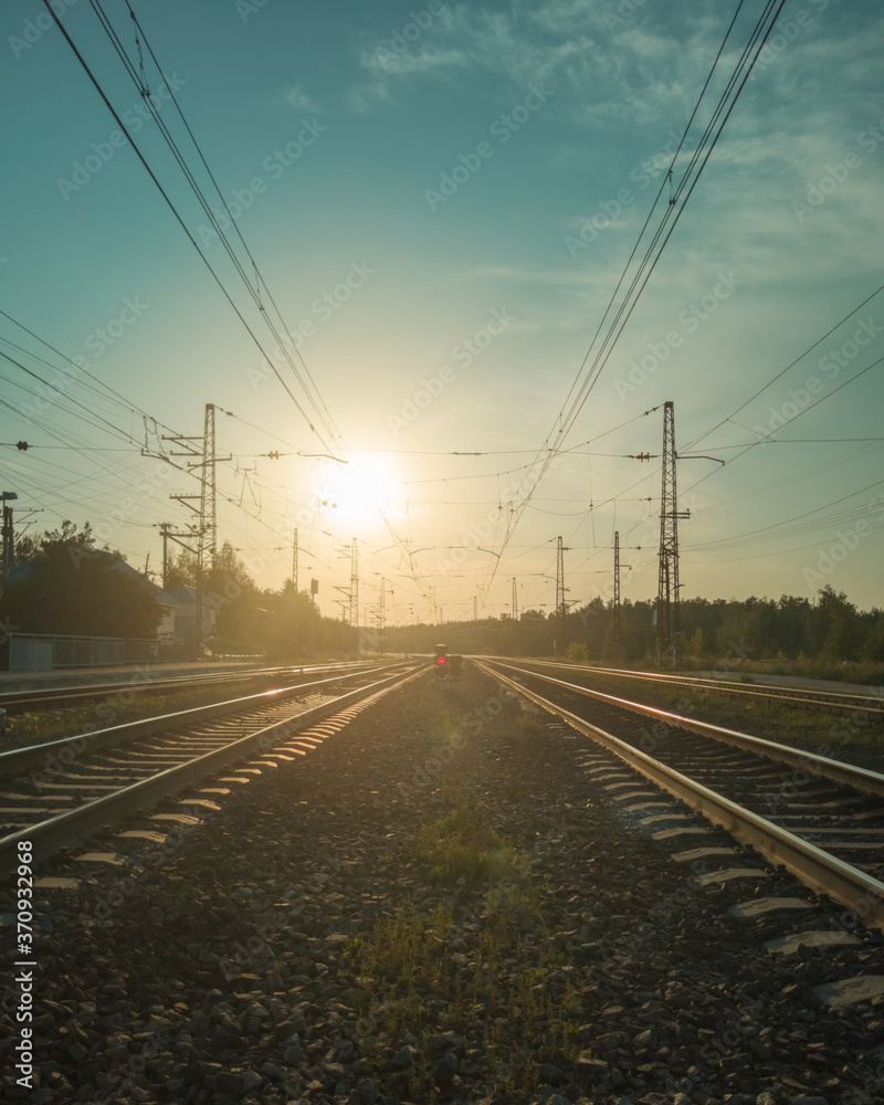 Landscape with railroad tracks and red signal semaphore in the rays of sunset