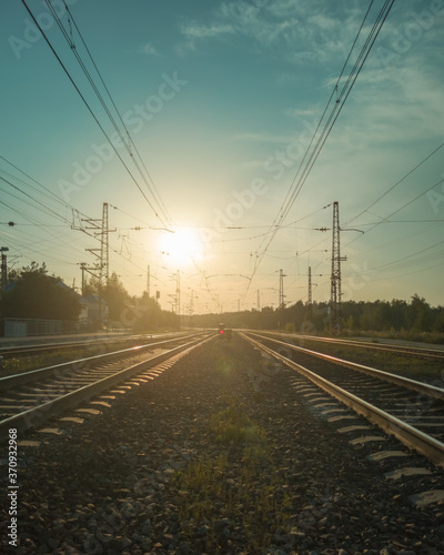 Landscape with railroad tracks and red signal semaphore in the rays of sunset