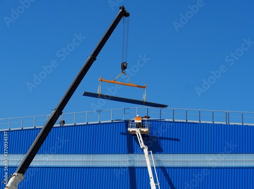 Foto Work aerial platform and telescopic crane at work on a facade of an industrial b