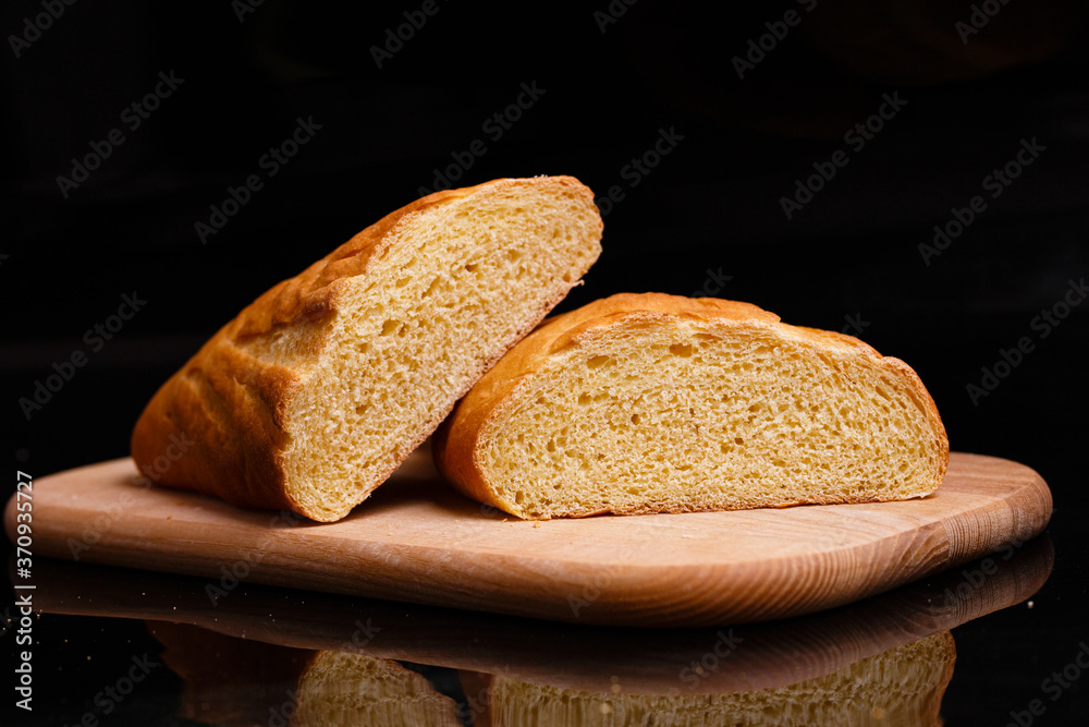 Naklejka premium Homemade bread. Baking at home. Round bread on a wooden board.