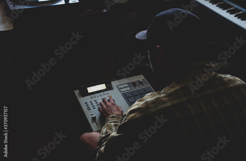 A hip hop composer, beatmaker creates beats on a digital production controller with pushbutton pads. The DJ plays the beats live on the pad controller of digital audio equipment. Rap music 