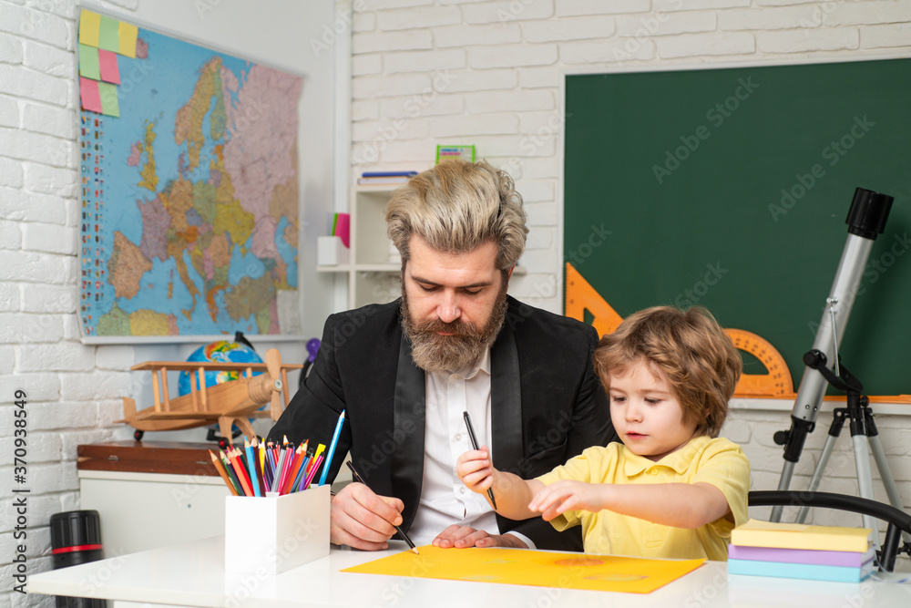 Little boy pupil with happy face expression near desk with school supplies. Individual teaching. Pupil of primary school study indoors.