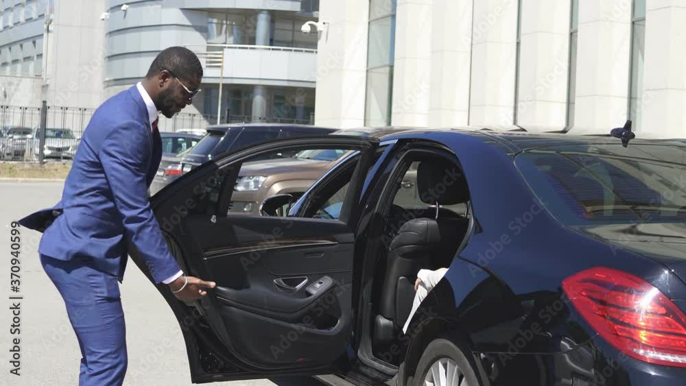Polite taxi driver help business woman get out of car, kind man give hand to woman in formal wear. Polite taxi driver help business woman get out of car, kind man give hand to woman in formal wear.