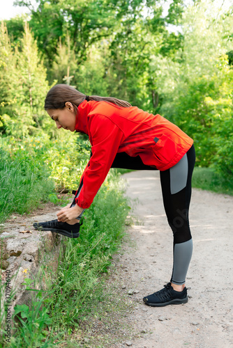 young girl tying shoelaces on sneakers before jogging in nature