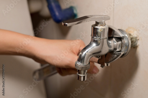 Foto Man fixing tap with pliers at home in the bathroom