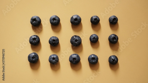 Blueberries are laid out in rows on a gold background - perfectionism concept