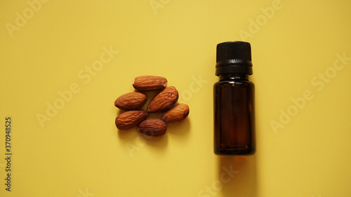 Bottle of almond oil and almonds on yellow background - Bottle and handful of nutsBottle and handful of nuts