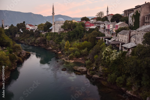 Obraz na płótnie Mostar village with mosque and houses reflected on the water of river during sunset time w salonie