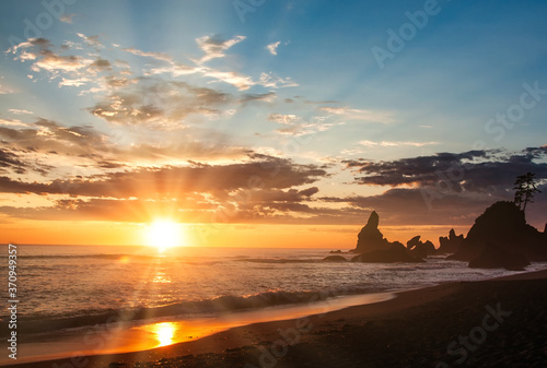 Surreal beach sunset - waves, rock formations and sun rays in sky at Shi Shi Beach Washington Pacific Northwest