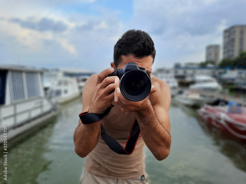 Photographer taking pictures at port with river, boats and yachts in the background