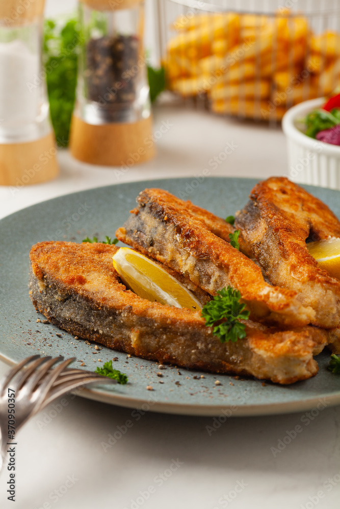 Fried carp in pieces, served on a gray plate. Marbled bright background. Fried carp in pieces, served on a gray plate. Marbled bright background.