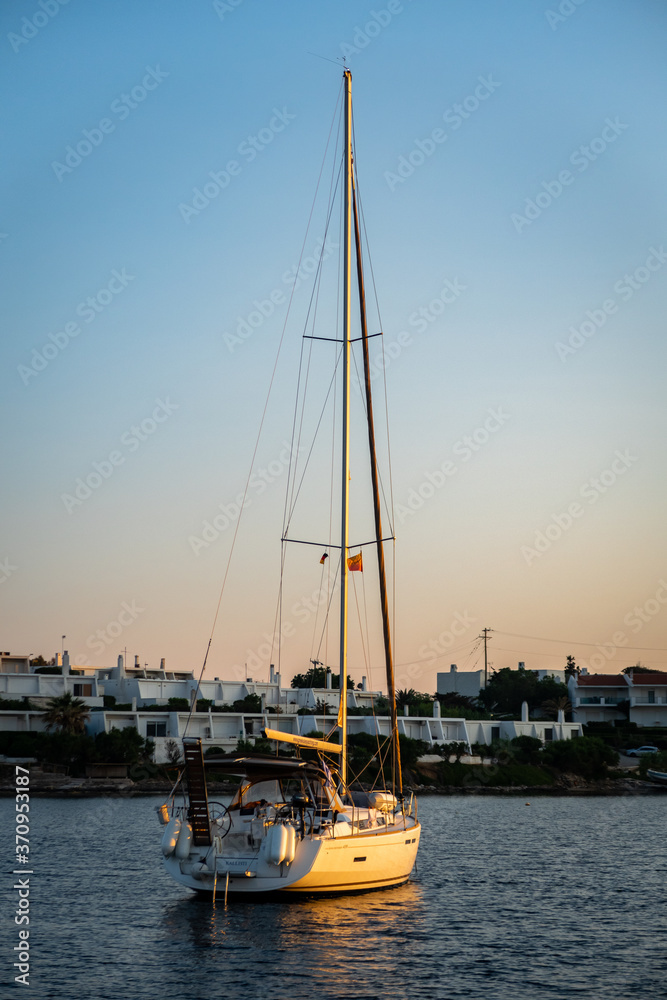 Portrait view of sailing yacht archored in Paralia Pountazeza bay in Greece on Mediterranean Sea with beautiful blue and orange sky during sunset.