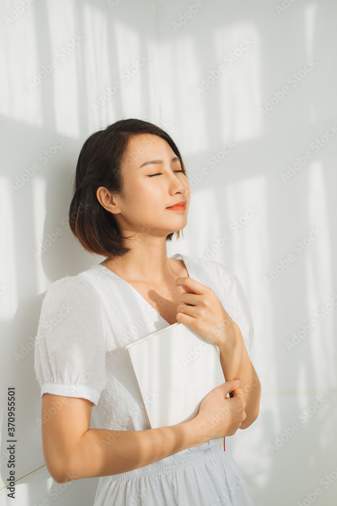 Portrait of beautiful asian woman relaxing by reading book near the window with sunlight of the morning