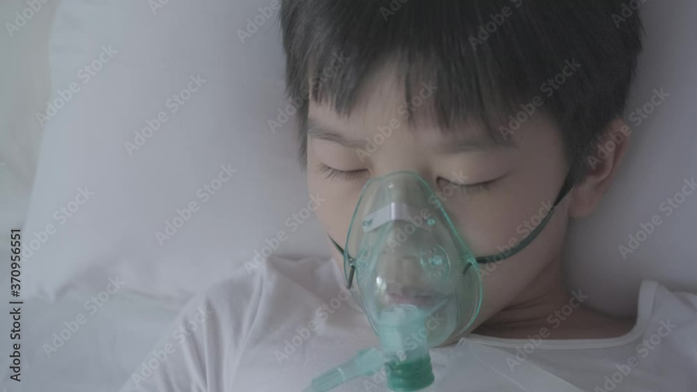 4k Top view Young asian boy with oxygen mask sleep on a bed looking outside of window with sad eye