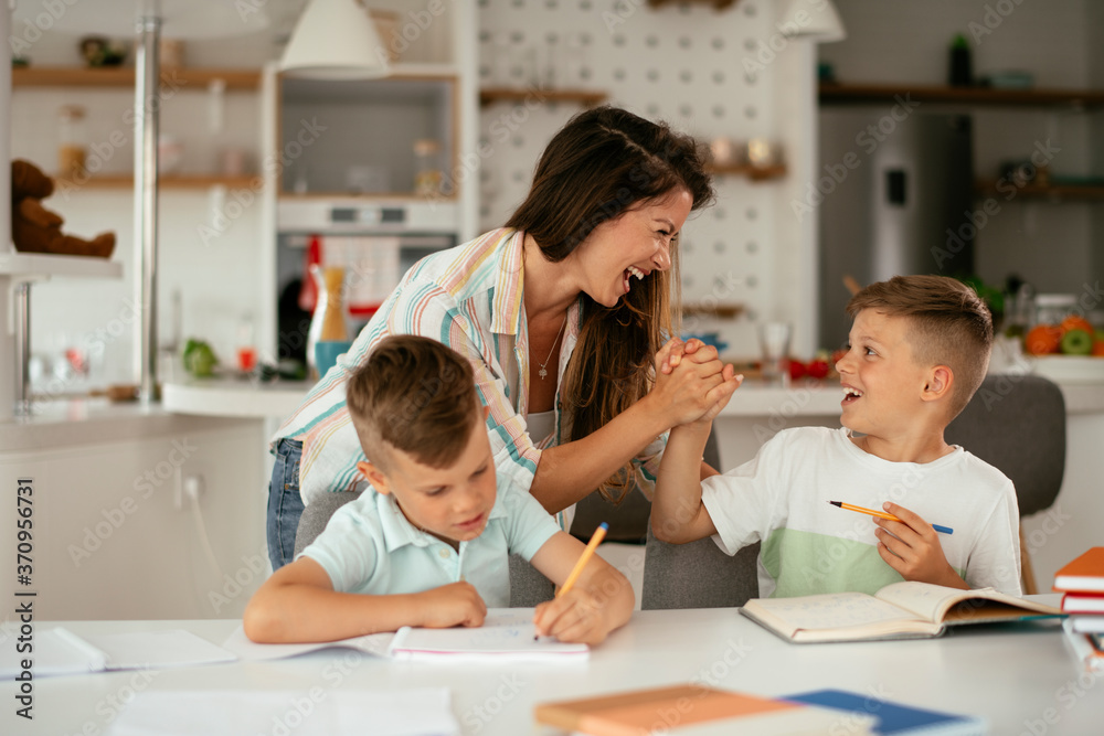 Mother helping her sons with homework at home. Little boys learning at home.. Mother helping her sons with homework at home. Little boys learning at home..