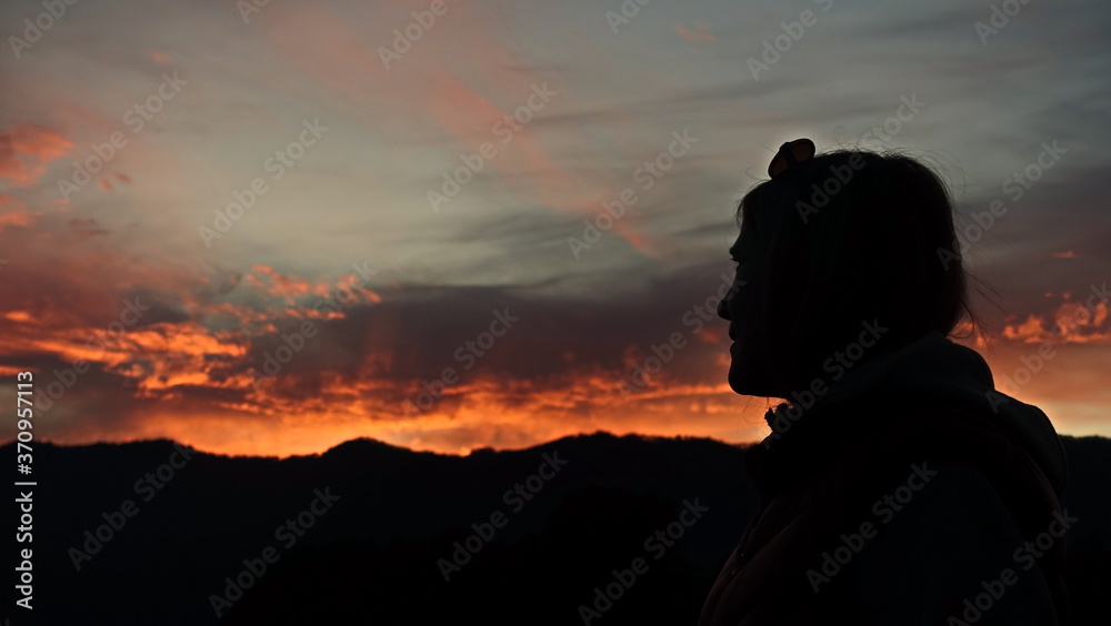Silhouette of a woman against the background of an orange sunset. Mountain Altai.