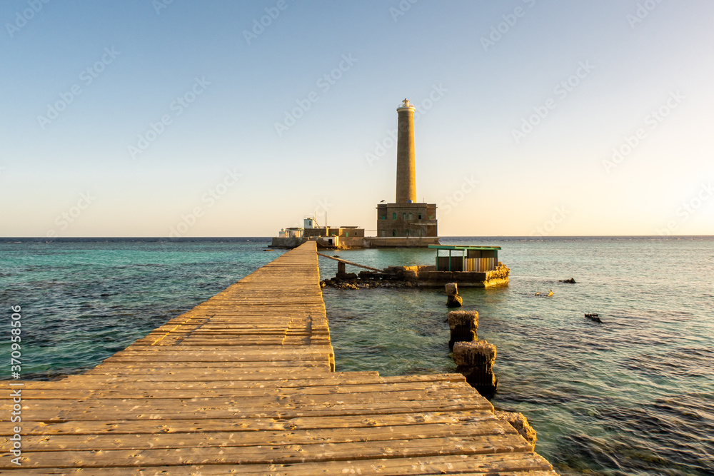 Sanganeb Reef Lighthouse near Port Sudan, on the Red Sea, in Sanganeb National Park, wooden pier view with a lighthouse in the distance, golden hour, before sunset.