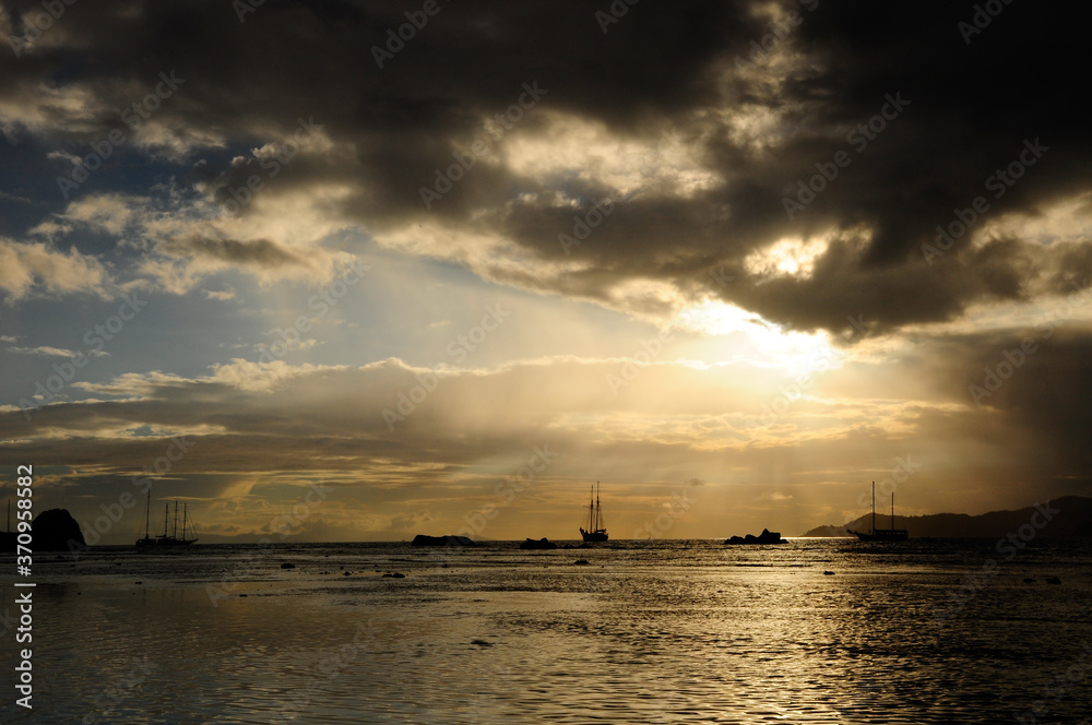 Dramatic sky with clouds and sunbeam over the Indian Ocean with sailing boat during sunset. Dramatic sky with clouds and sunbeam over the Indian Ocean with sailing boat during sunset.