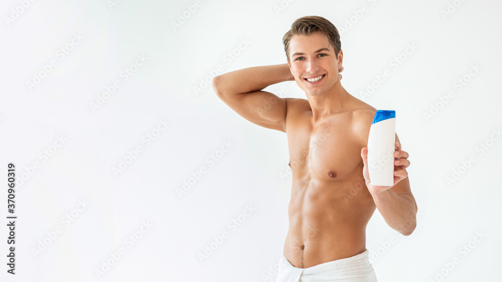 Handsome young man standing with shampoo in hands Handsome young man standing with shampoo in hands