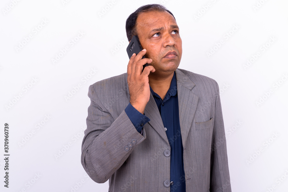 Portrait of mature overweight Indian businessman in suit talking on the phone Portrait of mature overweight Indian businessman in suit talking on the phone