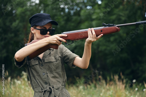 Military woman Holds weapon aiming sunglasses green overalls 