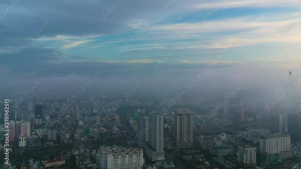 Early morning urban drone flight orbit around high rise buildings and major roads and bridge with heavy fog and low clouds Early morning urban drone flight orbit around high rise buildings and major roads and bridge with heavy fog and low clouds