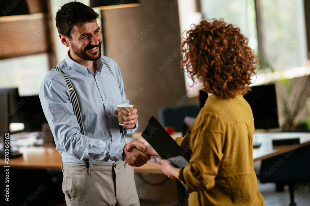 Colleagues in office. Businesswoman and businessman handshake in the office. Colleagues in office. Businesswoman and businessman handshake in the office.