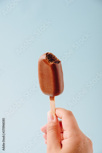 Chocolate cake in the form of ice cream on a stick on a white plate and a colored background