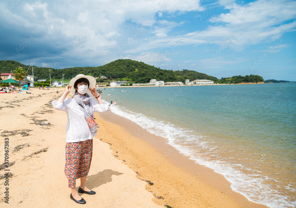 海岸を旅行中のマスクをした中年女性