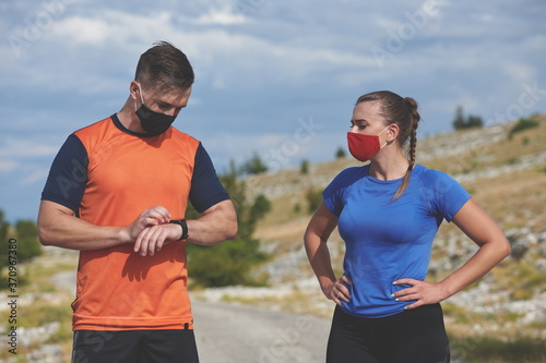 couple of running in nature wearing mask having a break