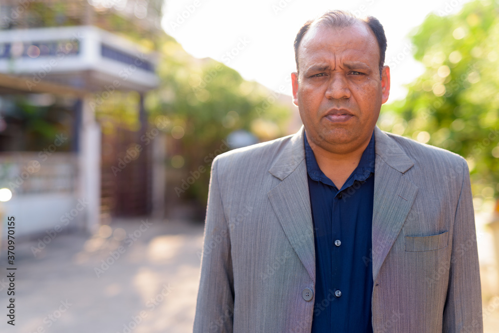 Portrait of mature overweight Indian businessman in suit outdoors Portrait of mature overweight Indian businessman in suit outdoors