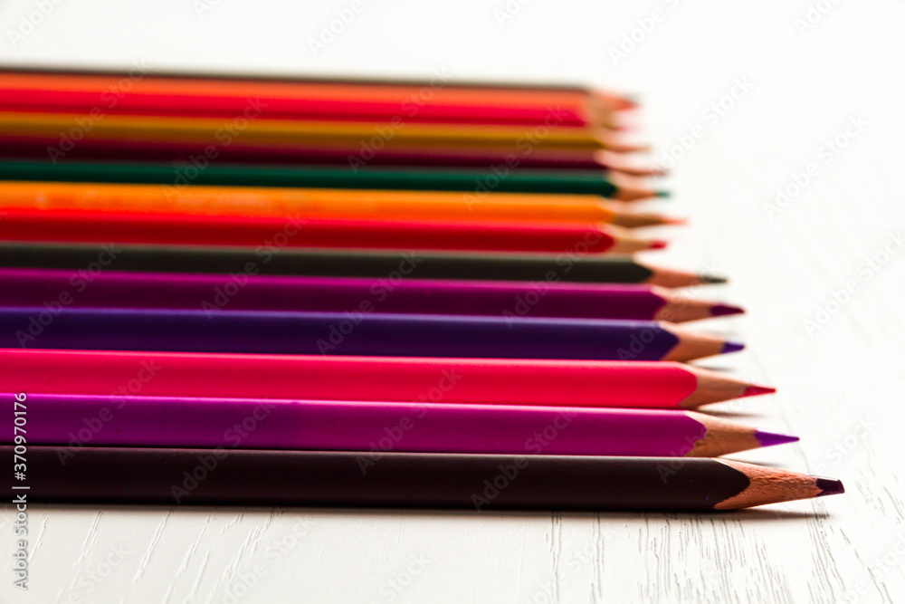 many colored sharpened pencils lie on a white wooden table many colored sharpened pencils lie on a white wooden table