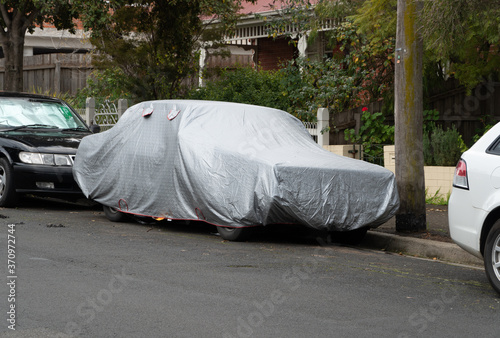 A car cover on an old car in a suburban street in Melbourne