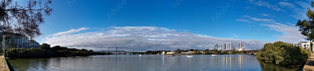Beautiful panoramic view of high-rise buildings on the riverbank on a sunny day with deep blue sky and light clouds, Parramatta river, Meadowbank, Sydney, New South Wales, Australia
