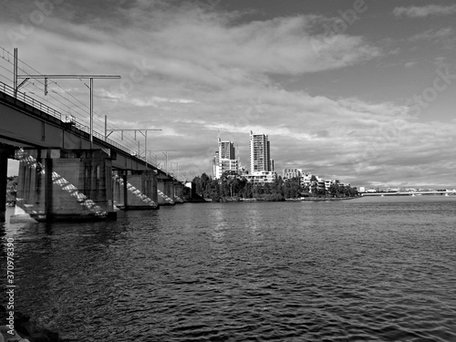 Beautiful black and white view of a railway bridge across a river and high-rise buildings on the riverbank, Parramatta river, Meadowbank, Sydney, New South Wales, Australia