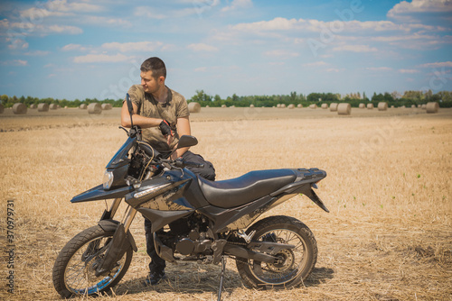 Young man on a motorcycle at field, hobby of modern people, lifestyle 
