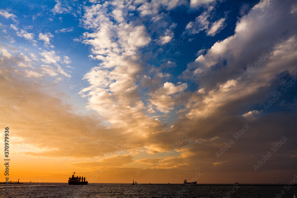 Sunset into the sea with the container ship silhouette.