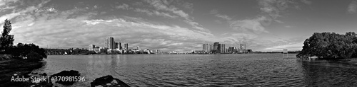 Beautiful black and white panoramic view of high-rise buildings on the riverbank on a sunny day with light clouds, Parramatta river, Meadowbank, Sydney, New South Wales, Australia 